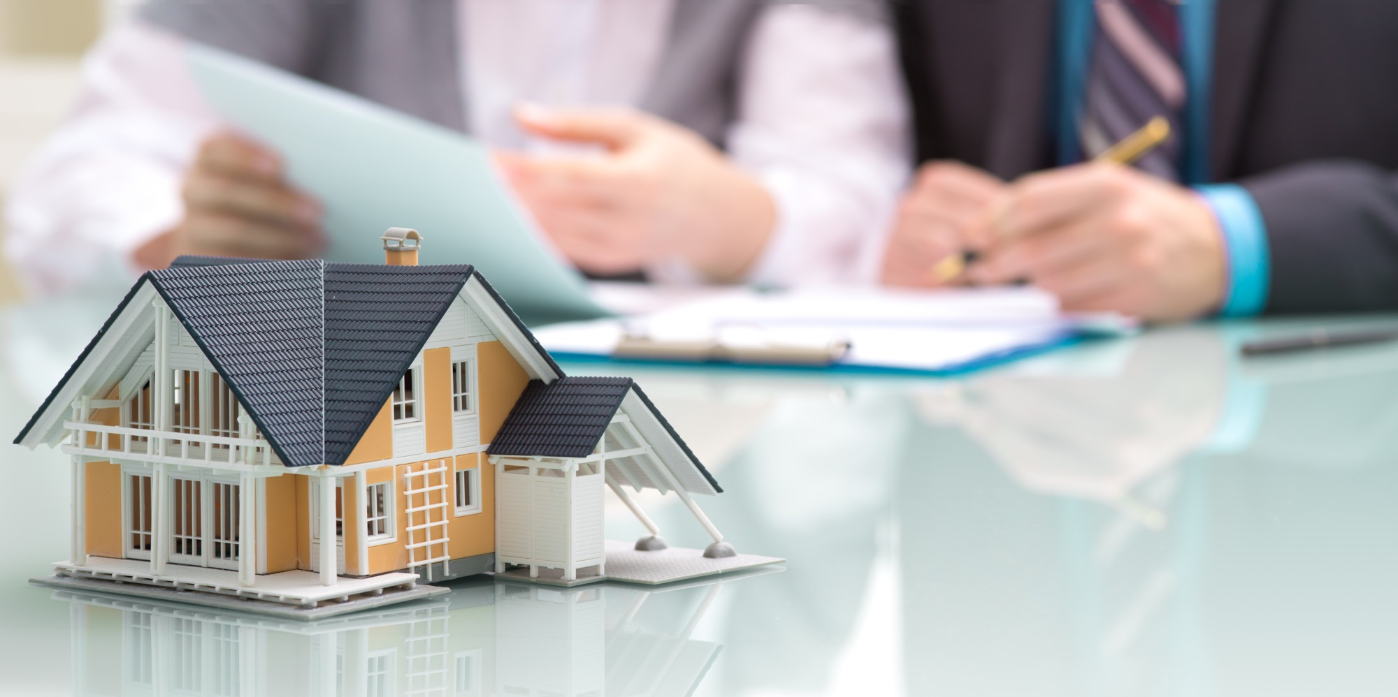 Businessman signs contract behind home architectural model